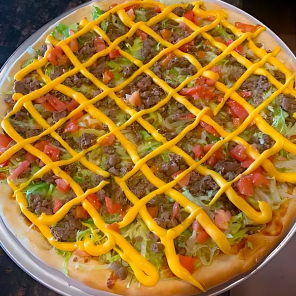 A taco pizza from 2 Brothers Pizzeria, topped with ground beef, lettuce, tomatoes, and cheese sauce.